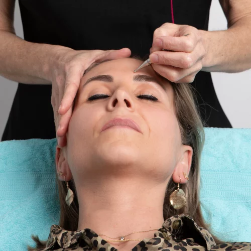 Valérie Perriguey réalise un soin de réflexologie avec un outil sur la tête d’une cliente, illustrant son accompagnement personnalisé et son expertise dans le bien-être à domicile.