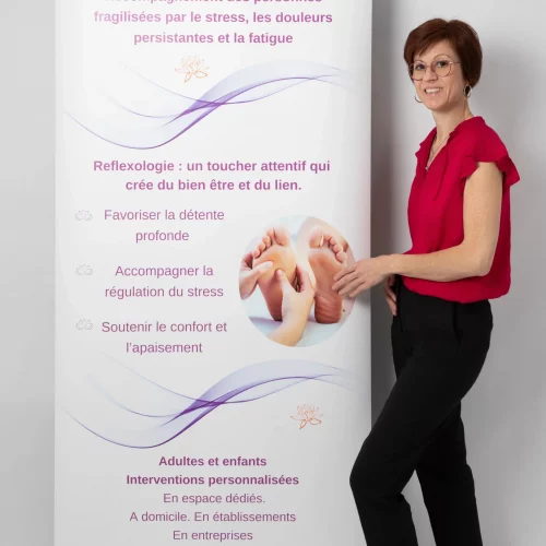 Valérie Perriguey devant une bâche publicitaire, présentant son activité de réflexologue à domicile.